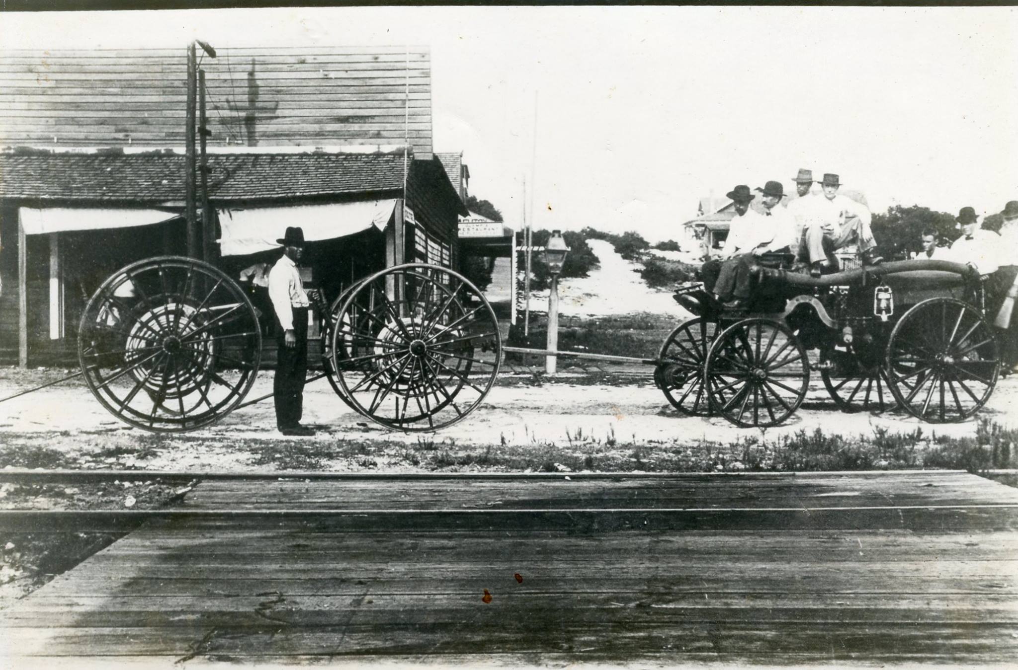 Early 1913 Fire Truck with several men sitting on top and one standing