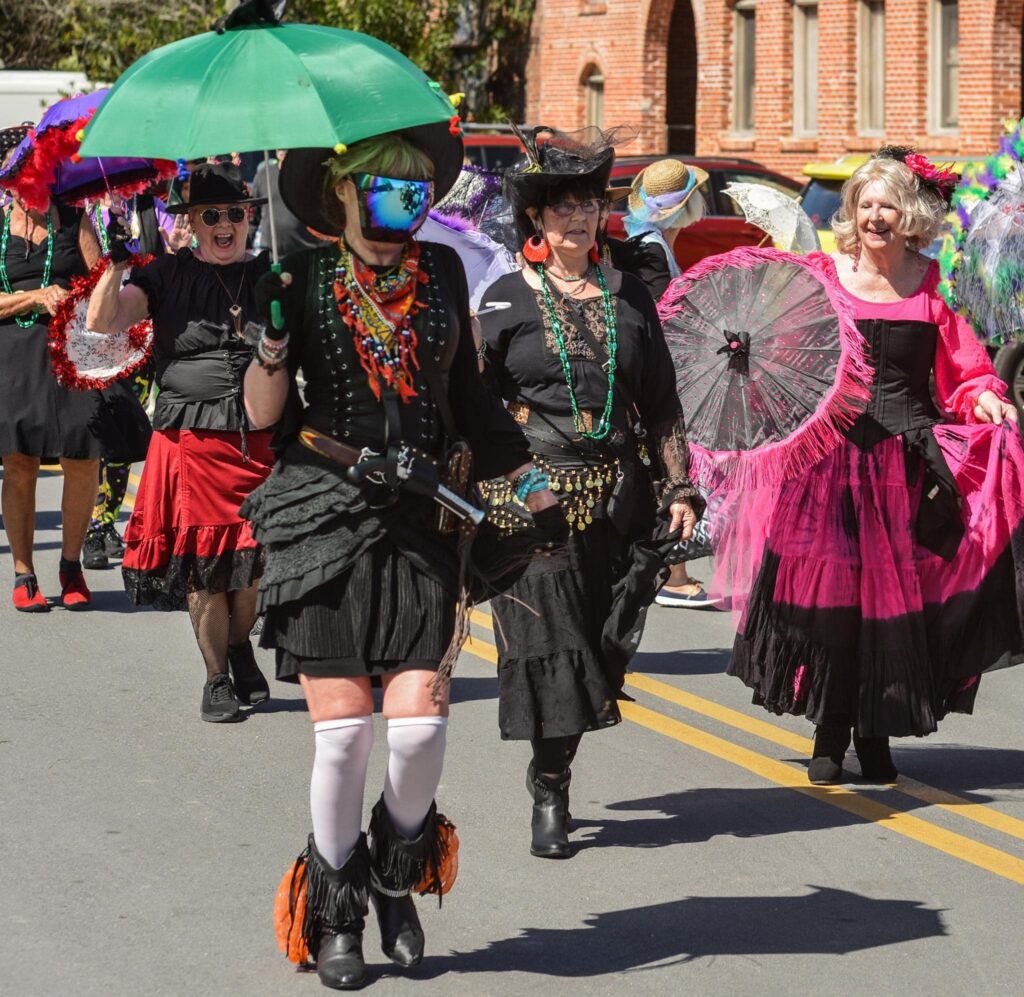 Group of women wearing colorful witch outfits walk down the street