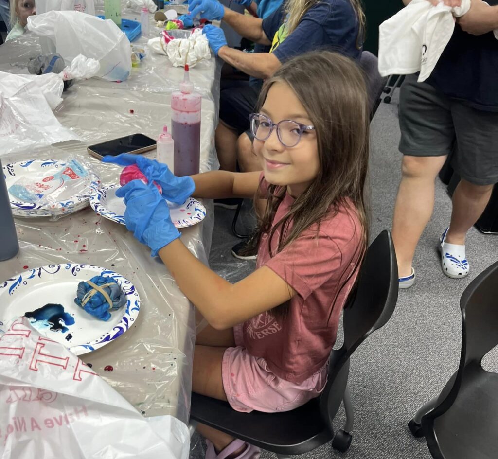 Girl sits at a table doing arts and crafts