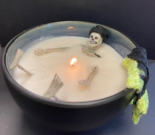 A small skeleton figurine sits in a bath like candle