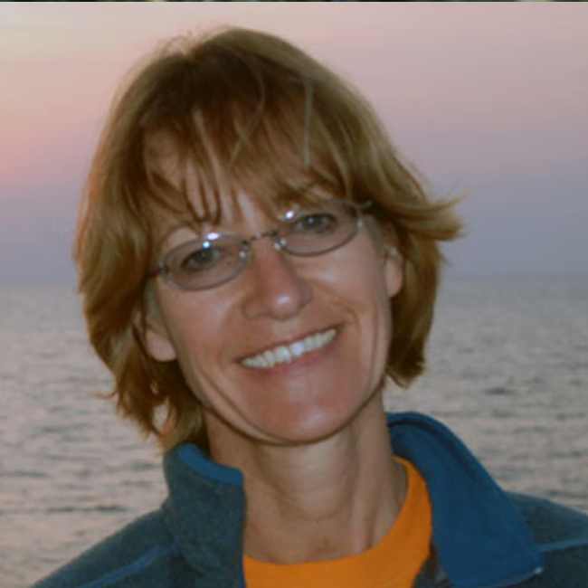 Woman smiles with the sunset behind her