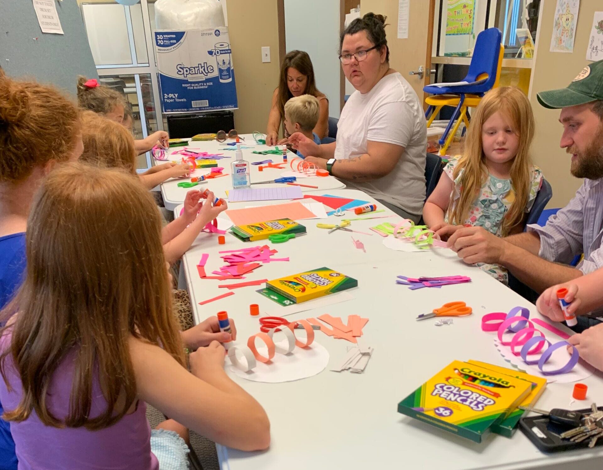 Kids and adults sit around a table doing crafts